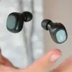 A pair of black QCY wireless earbuds featuring Environmental Noise Cancellation technology floating above an open hand