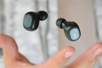 A pair of black QCY wireless earbuds featuring Environmental Noise Cancellation technology floating above an open hand