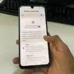 Hand holding smartphone displaying battery protection menu when fast charging stops at 80%