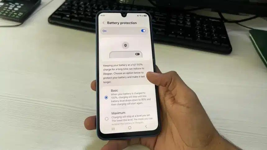 Hand holding smartphone displaying battery protection menu when fast charging stops at 80%