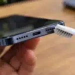 Cleaning a phone speaker grille with a soft brush to remove dust