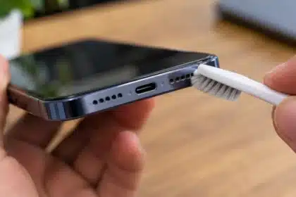 Cleaning a phone speaker grille with a soft brush to remove dust